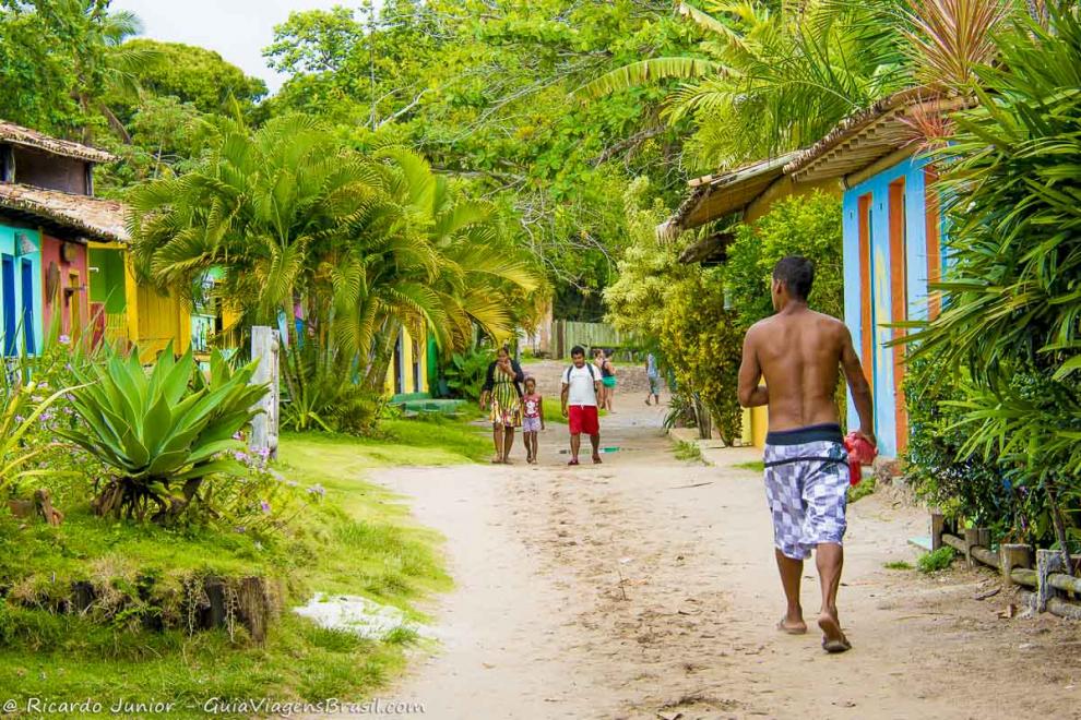 Imagem de crianças e adultos andando pelas ruas estreitas e de areia no vilarejo em Caraiva.